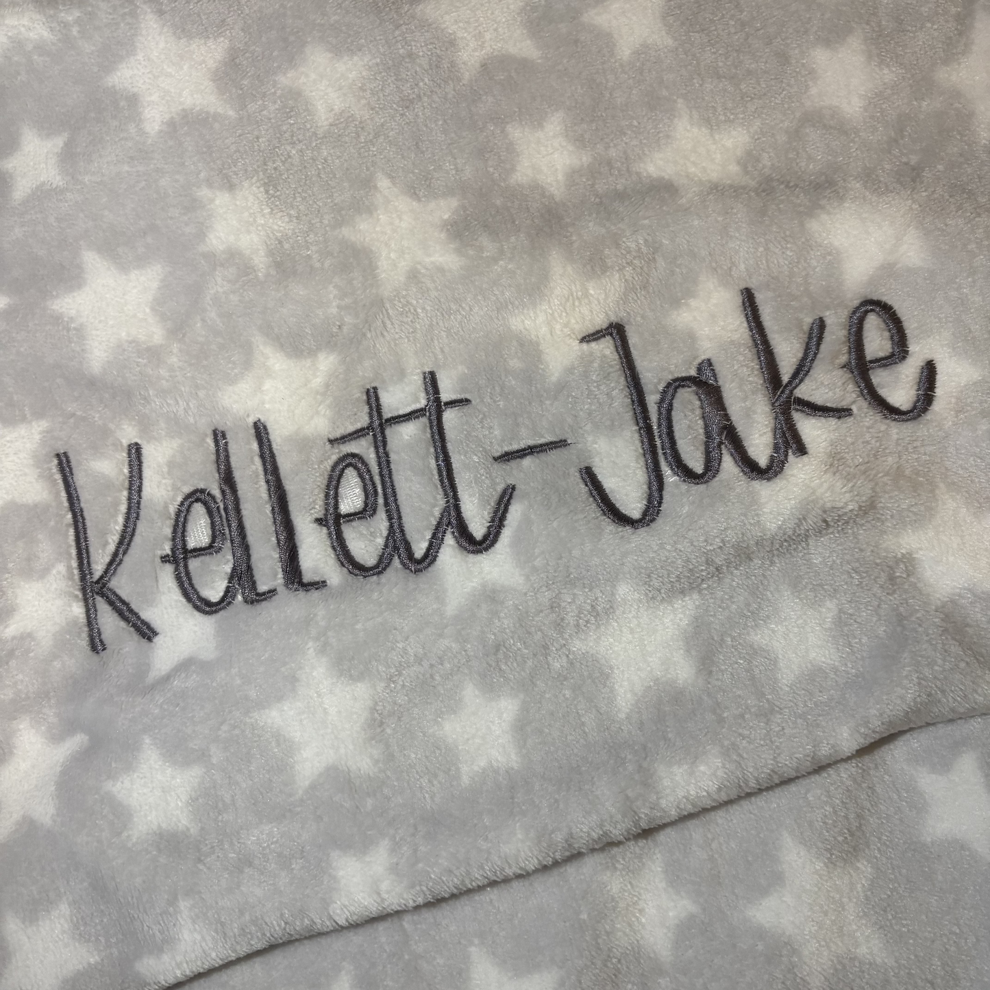 Grey baby blanket with a name embroidered on it