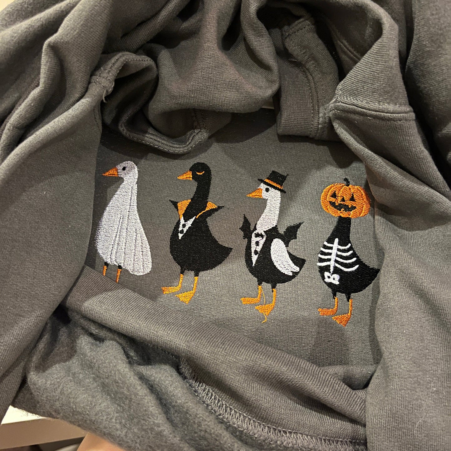 Gray sweatshirt with Halloween-themed embroidery of ghosts and pumpkins.