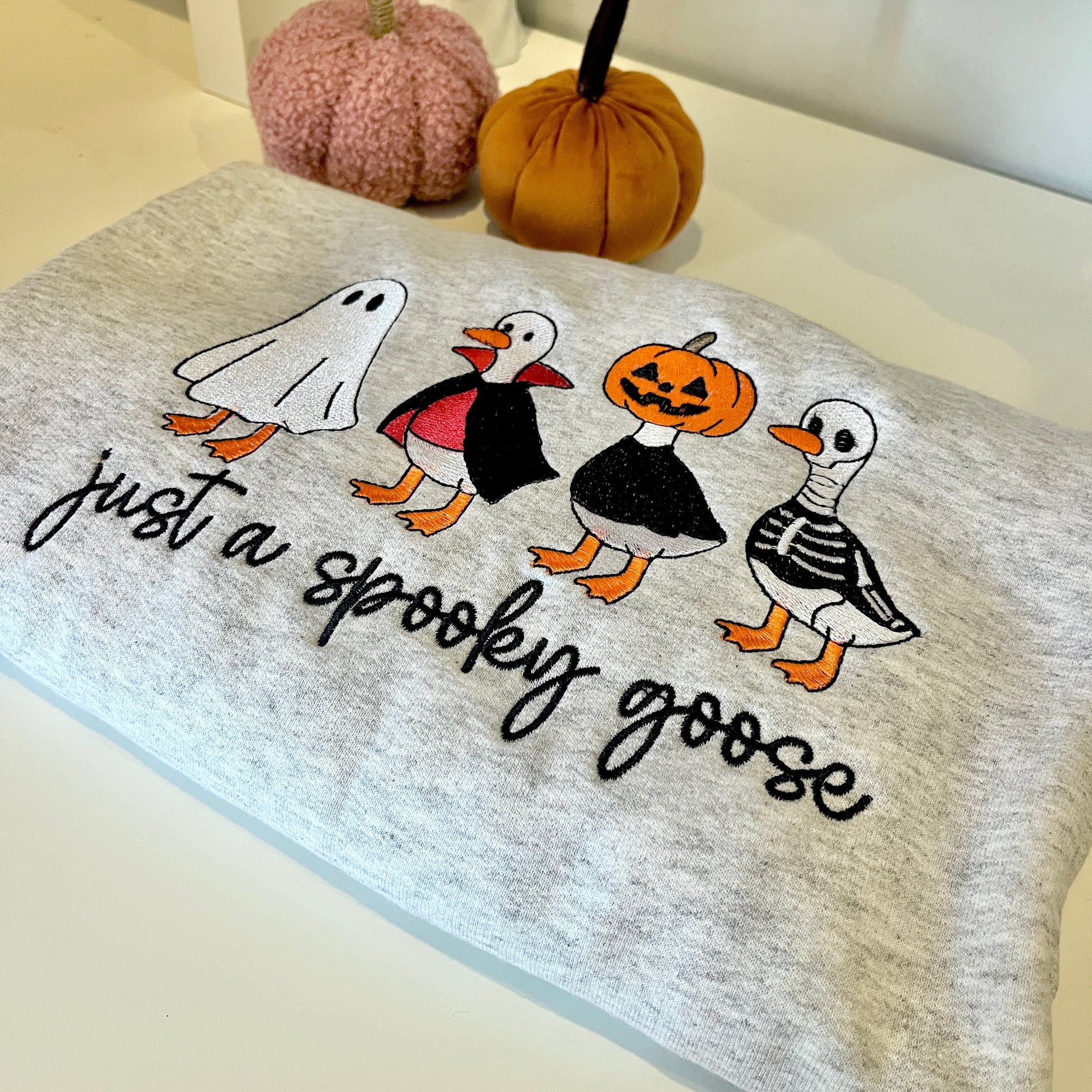 Gray sweatshirt with Halloween-themed graphic of geese and text 'Just a spooky goose'.