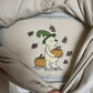 Beige sweatshirt with embroidered design of a bear wearing a witch hat and holding a pumpkin