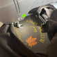 Embroidery machine with a piece of fabric featuring 'Stars Hollow 1779' and a maple leaf design.