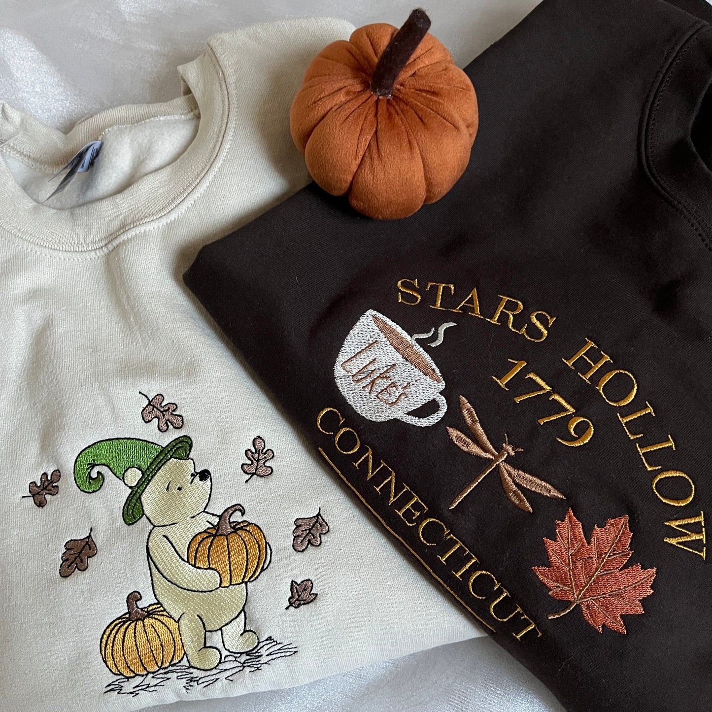 Brown sweatshirt with 'Stars Hollow 1779' embroidery and a beige sweatshirt with embroidered design 