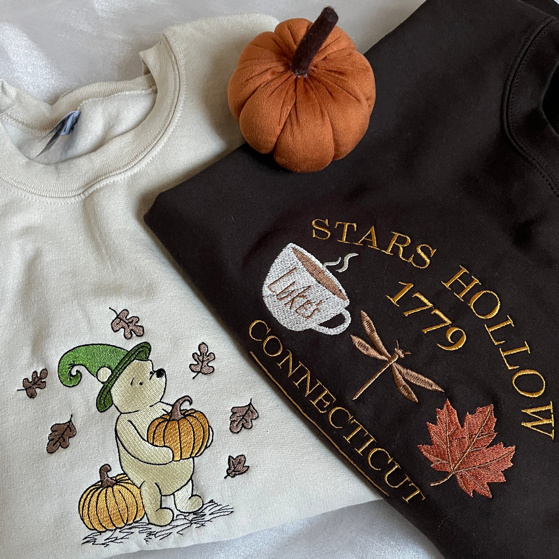 Brown sweatshirt with 'Stars Hollow 1779' embroidery and a beige sweatshirt with embroidered design 